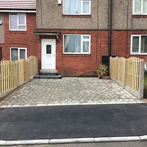 a brick driveway with a wooden fence around it