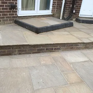 A brick patio with steps leading up to a door.