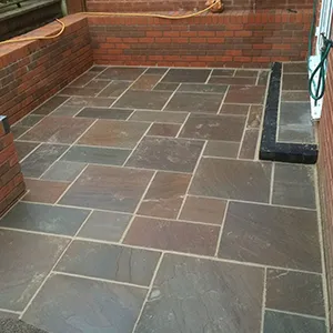 A patio with a brick wall and stone floor.