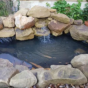 a pond with rocks and a waterfall in it